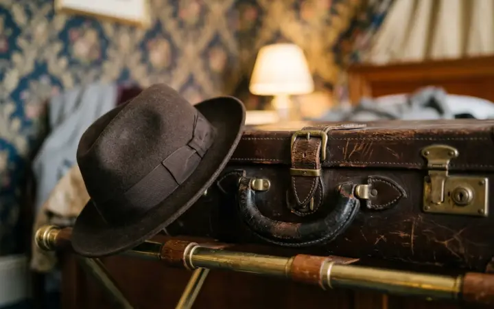 Old leather suitcase and a hat in a classic room (illustrative AI image)